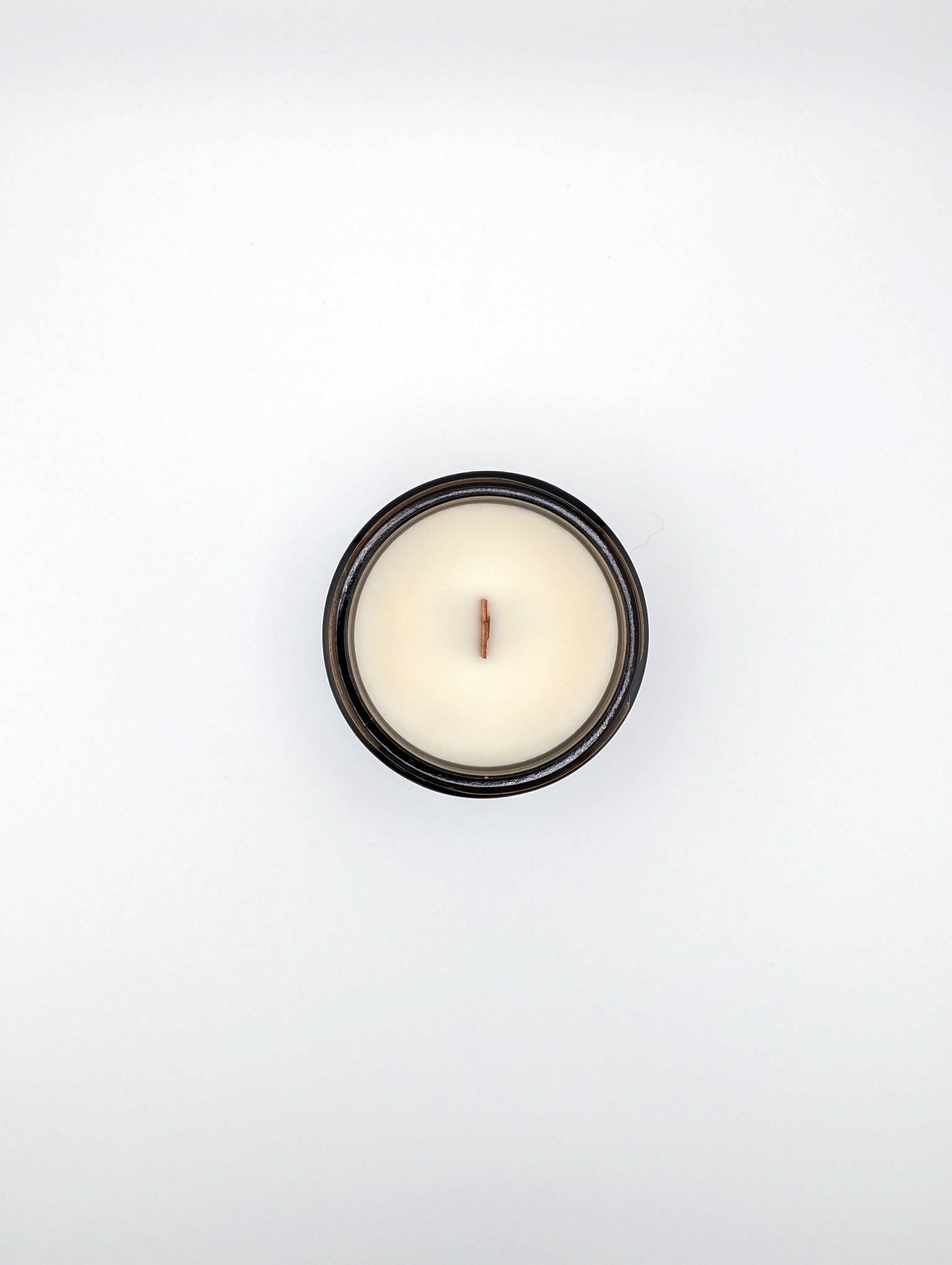 Small white candle in a black holder on a light gray background