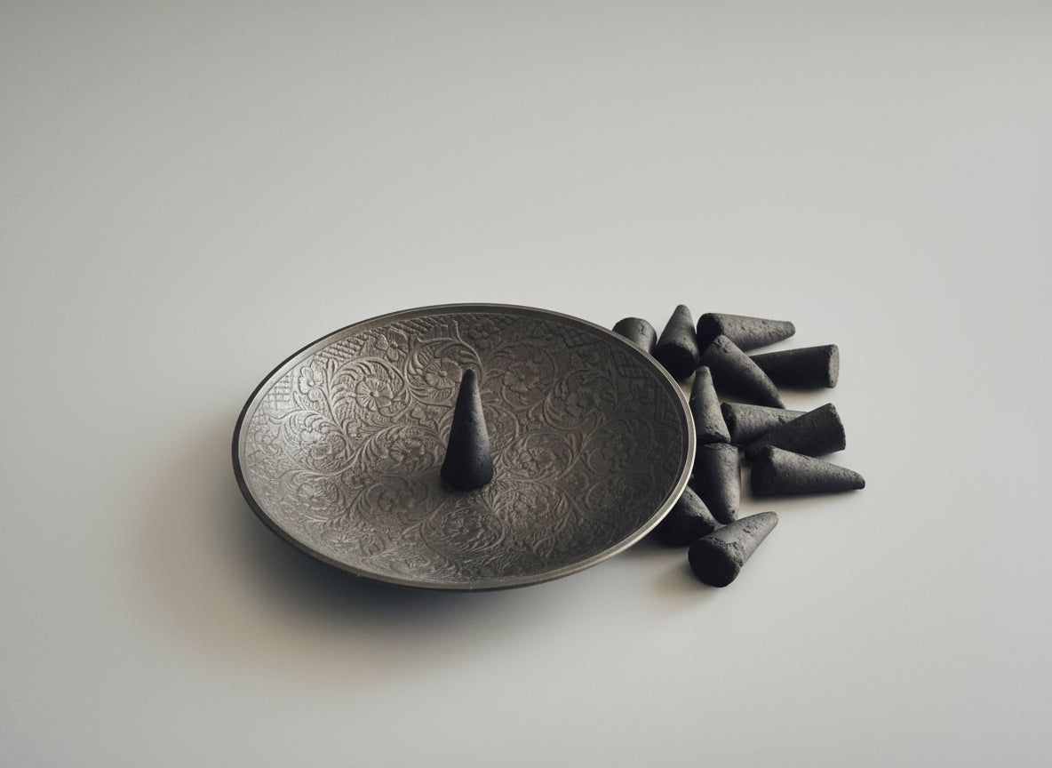 Incense cones on a decorative metal plate with intricate patterns