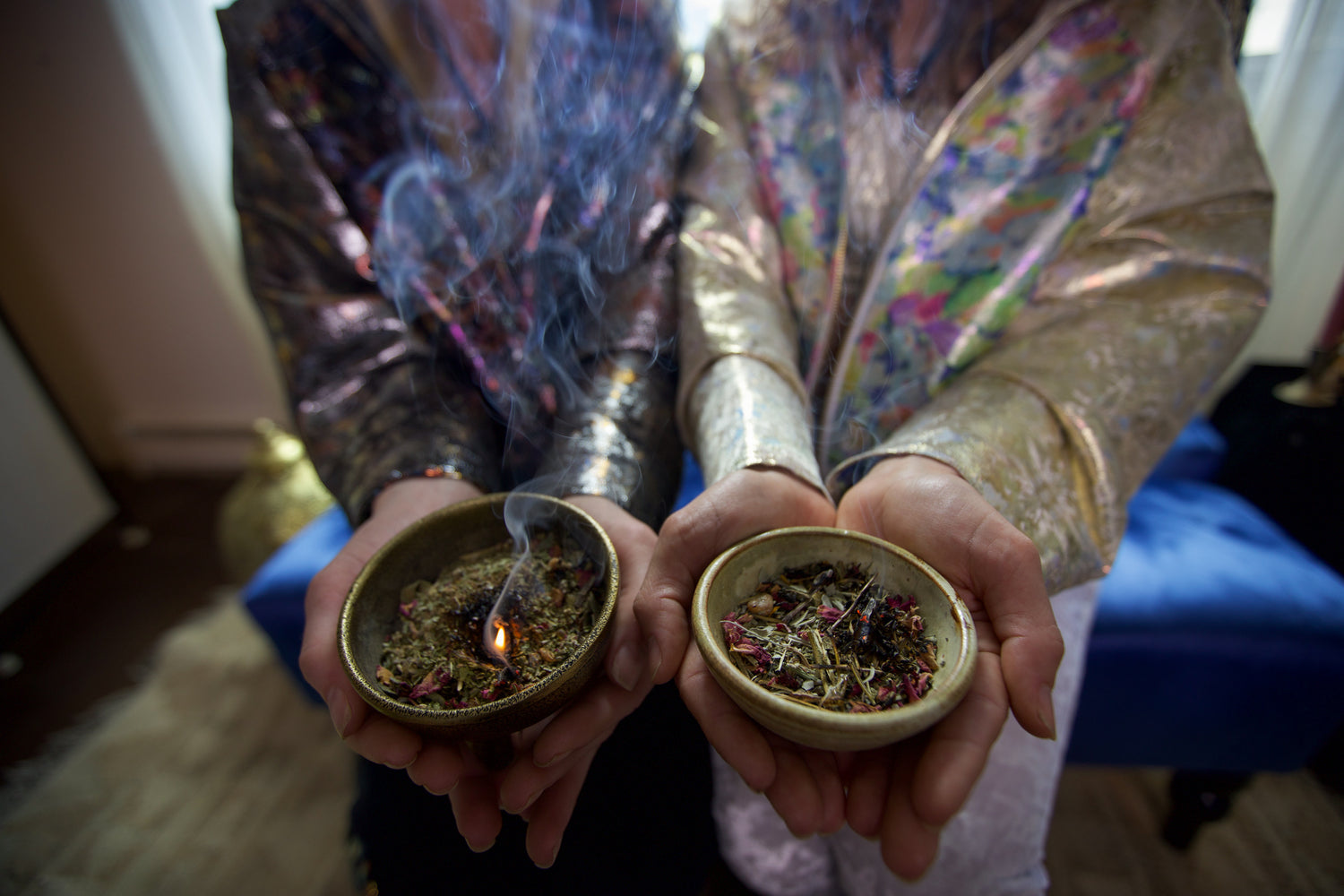 two women holding ceramic bowls filled with herbs and resin burning as loose incense