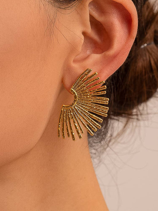 Gold sunburst earrings in a womans ear
