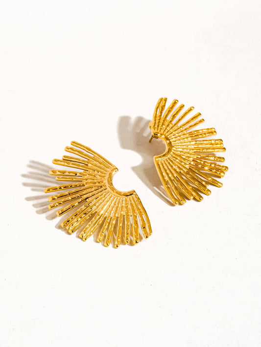 Gold sunburst earrings on a white background
