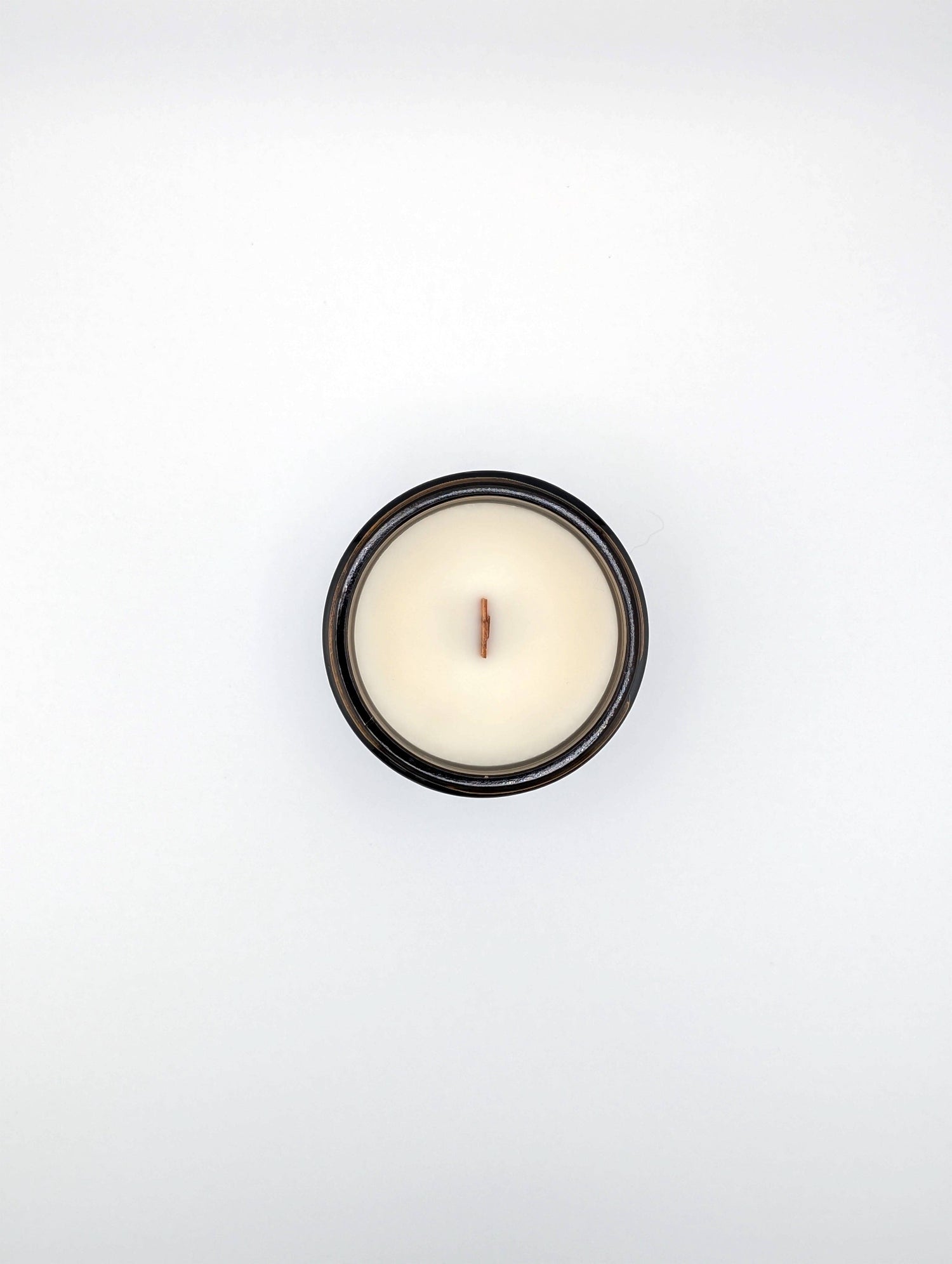Small white candle in a black holder on a light gray background