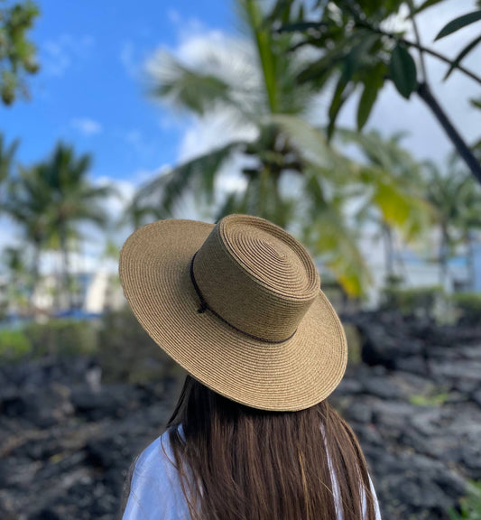 Person wearing a straw hat with palm trees and blue sky in the background