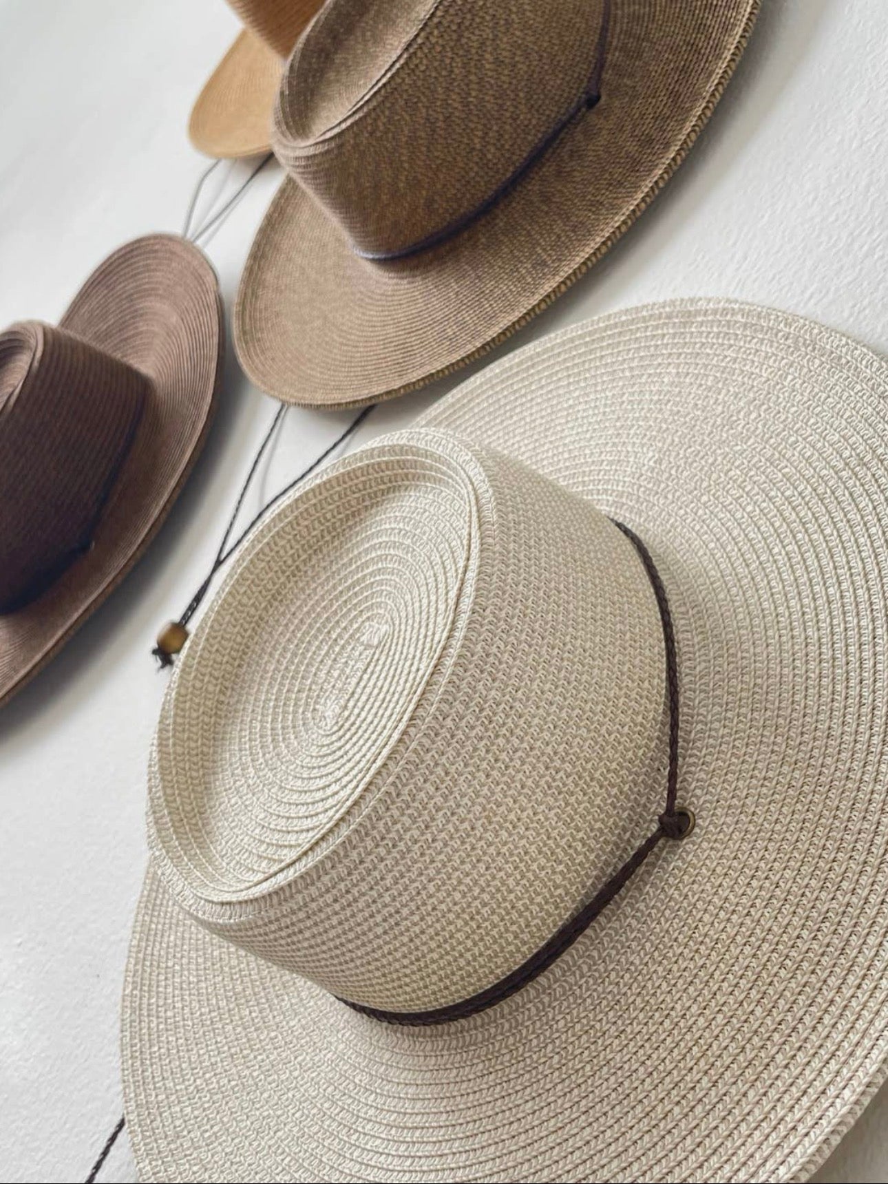 Three straw hats in different colors on a light background