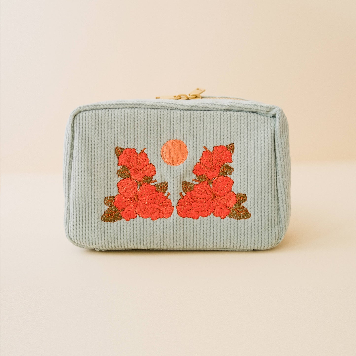 Light blue pouch with floral embroidery on a beige background