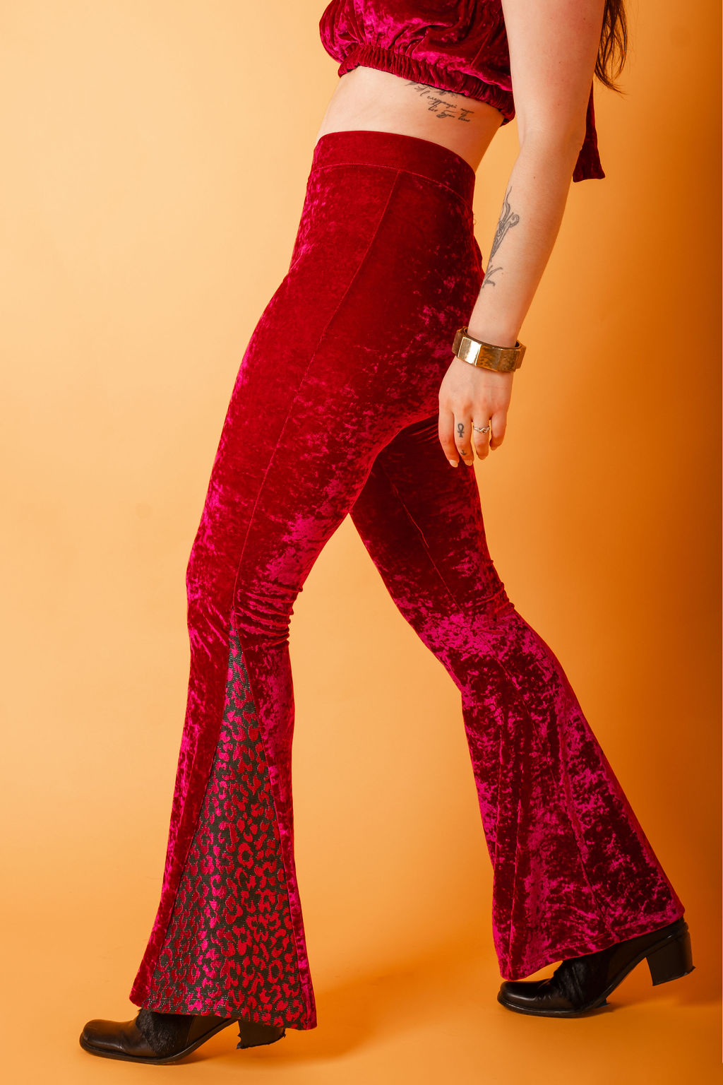 woman is standing in fuchsia crushed velvet high waisted pants with pink and green leopard brocade panels