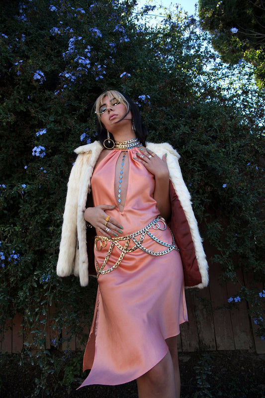 Woman standing in pink dress wearing gold chain belt