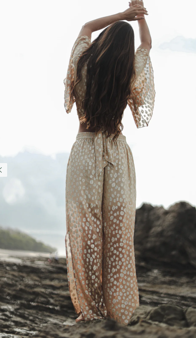 Woman in a patterned outfit standing on a rocky beach