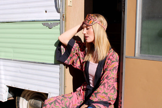 Woman in a floral robe sitting outside a trailer