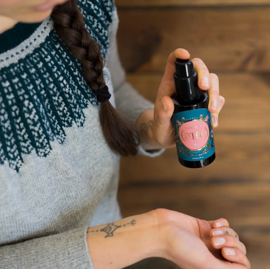 woman in wearing knit sweater is spraying joy aromatherapy mood spray on her wrist