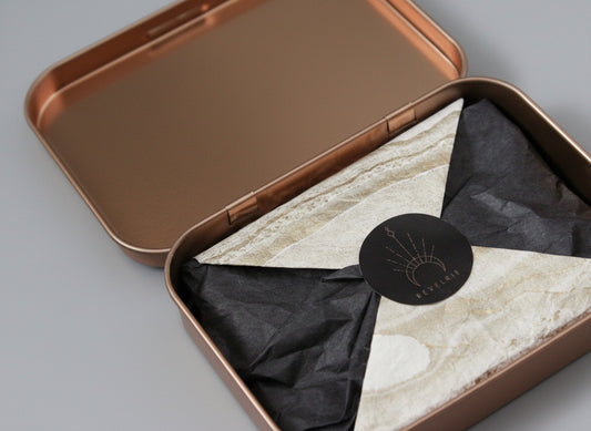 Open bronze-colored tin with marble-patterned interior and black label on a dark background