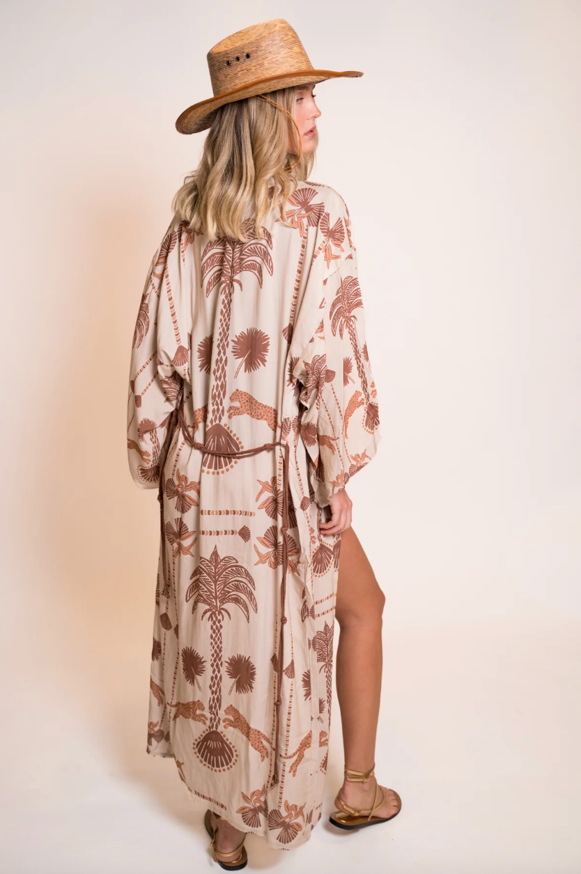 Woman wearing a patterned dress and hat on a plain background