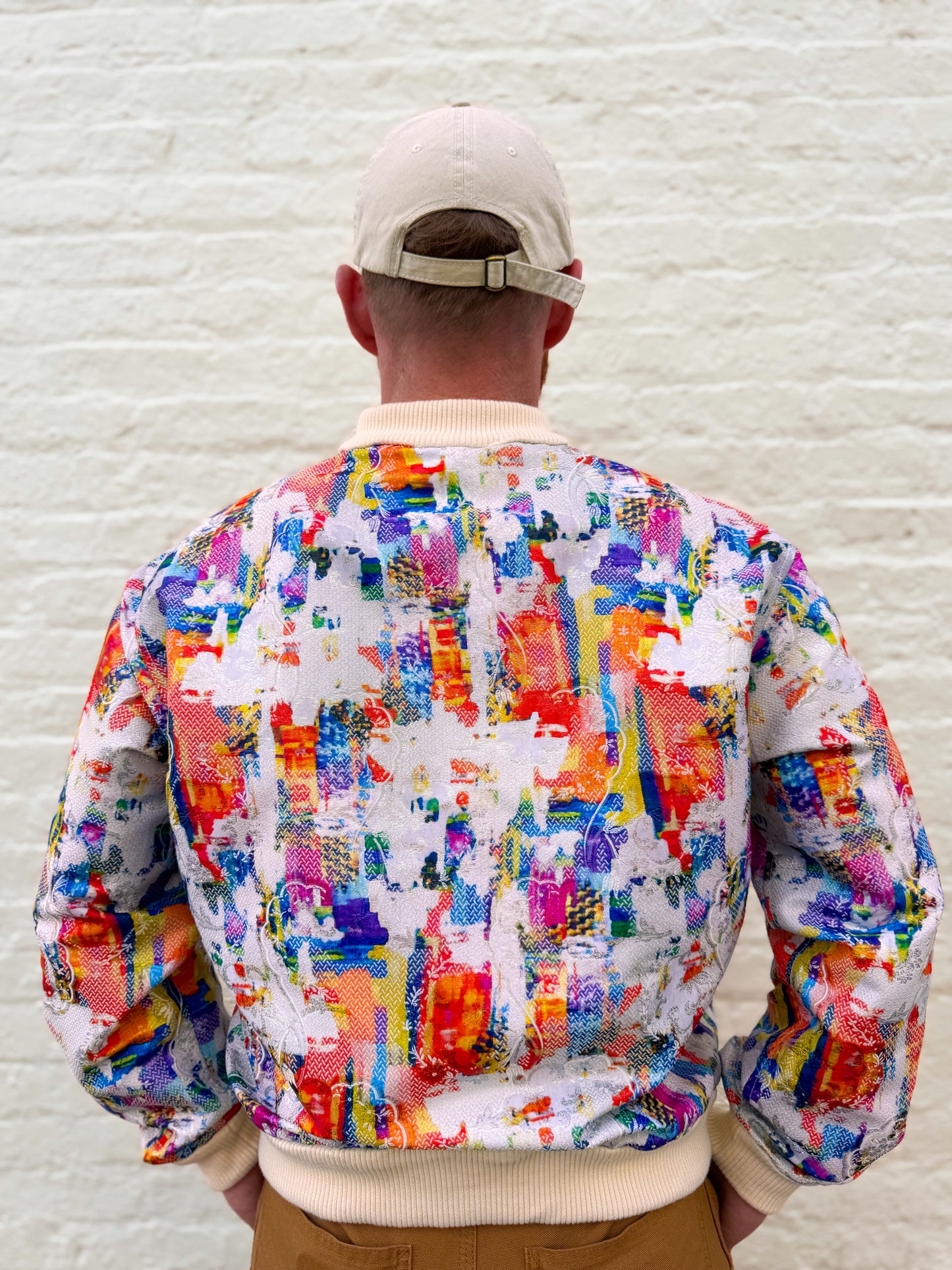 Person wearing a colorful jacket with a white brick wall background