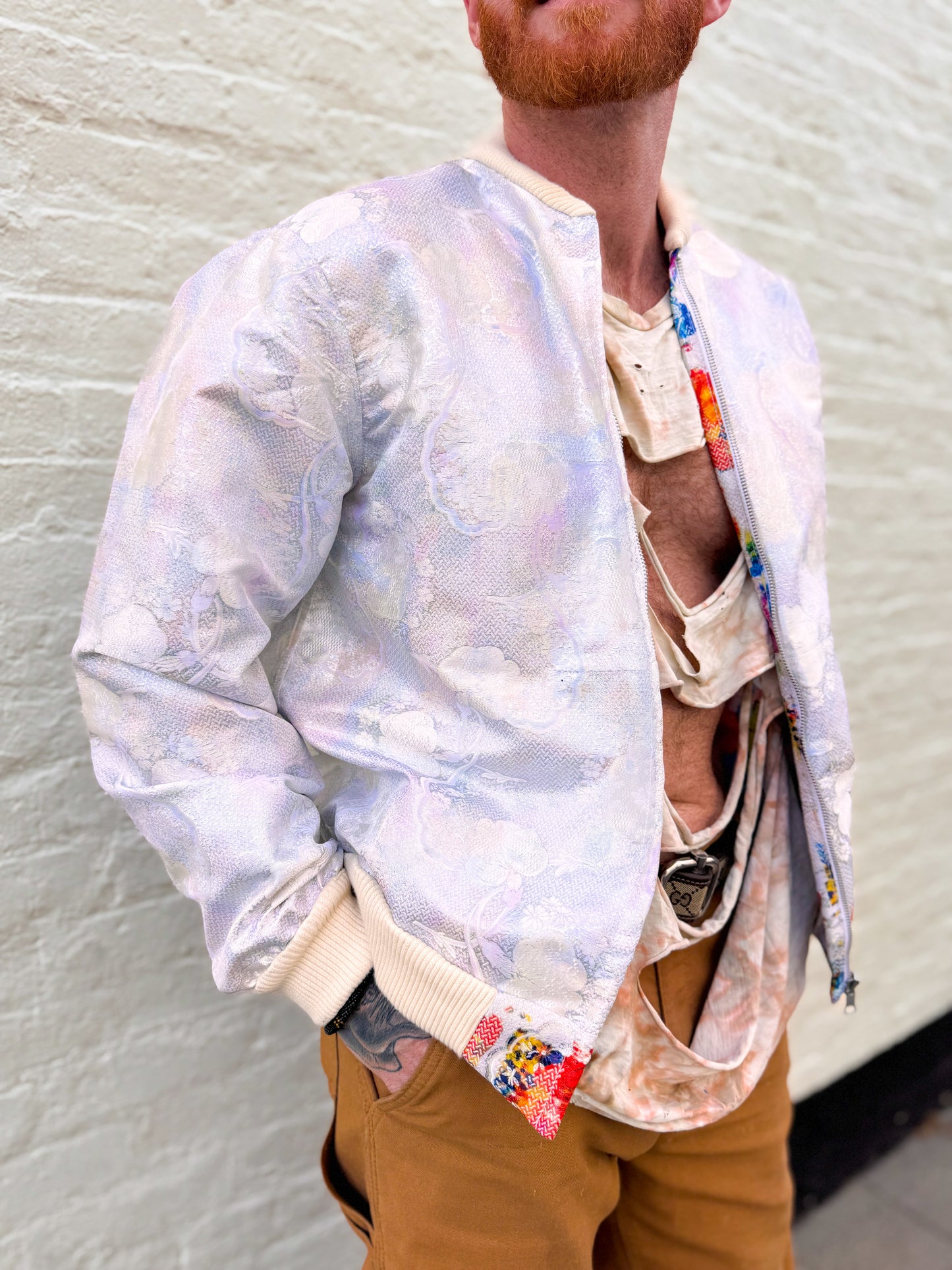 Person wearing a light-colored bomber jacket with a textured background