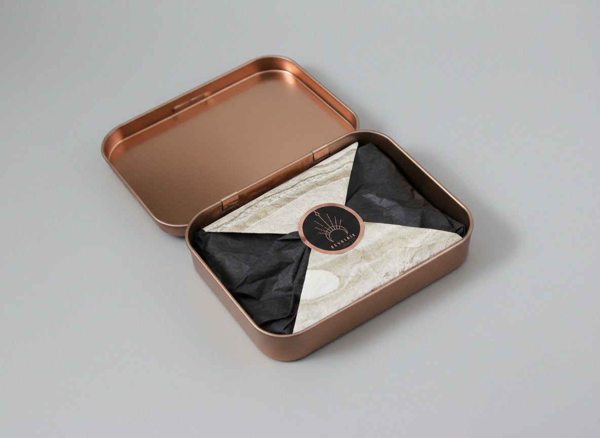 Open bronze-colored tin with marble-patterned interior and black label on a dark background