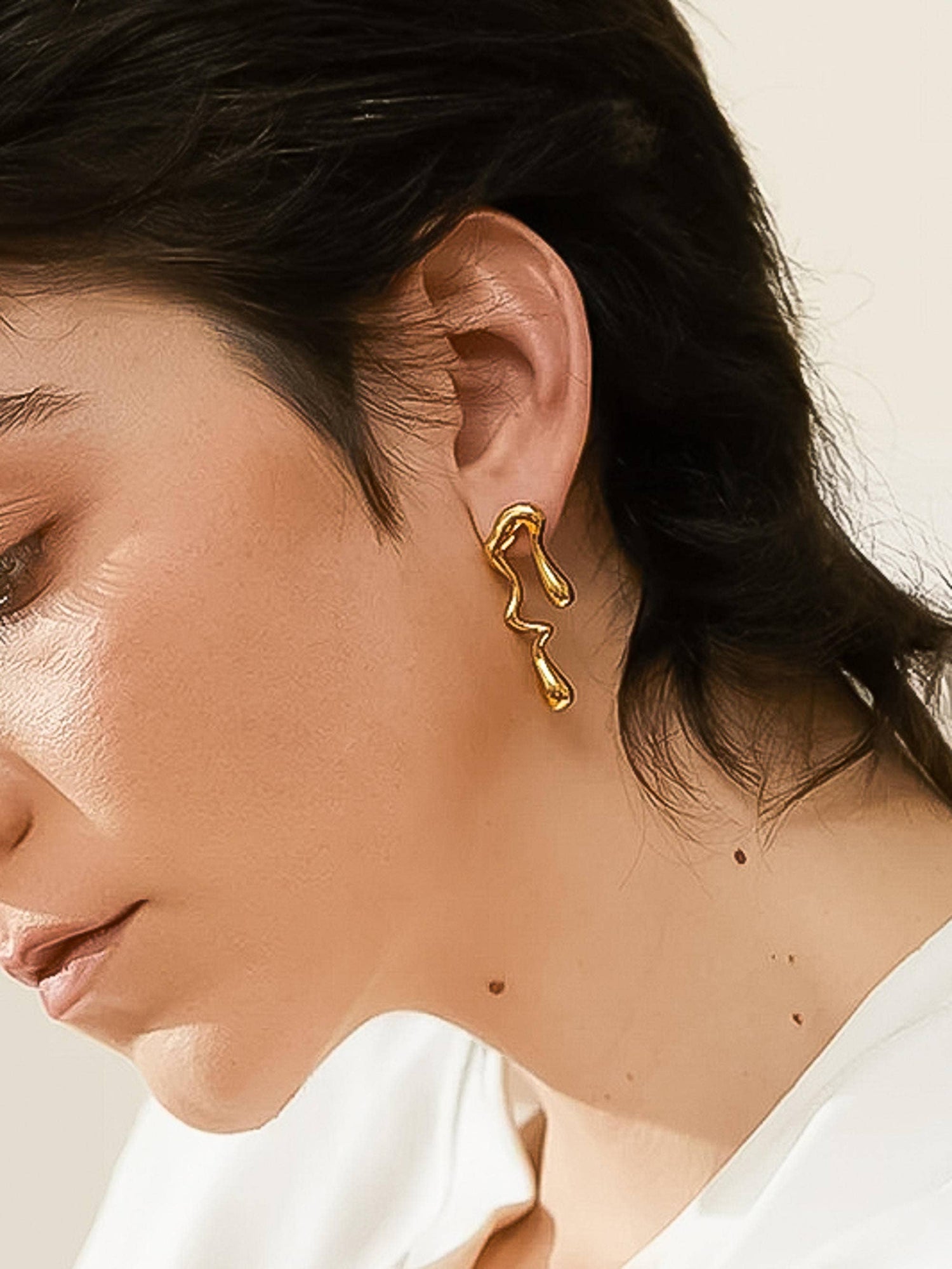 molten gold earring on a woman's left ear