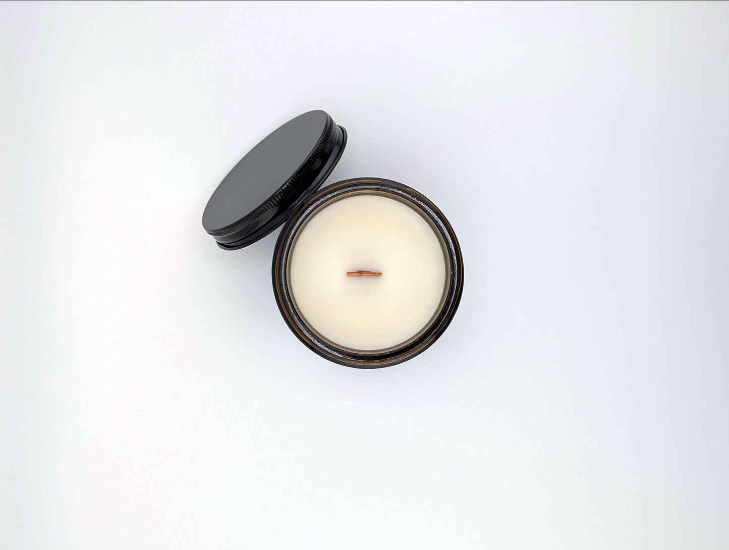 Candle in a tin with a black lid on a white background