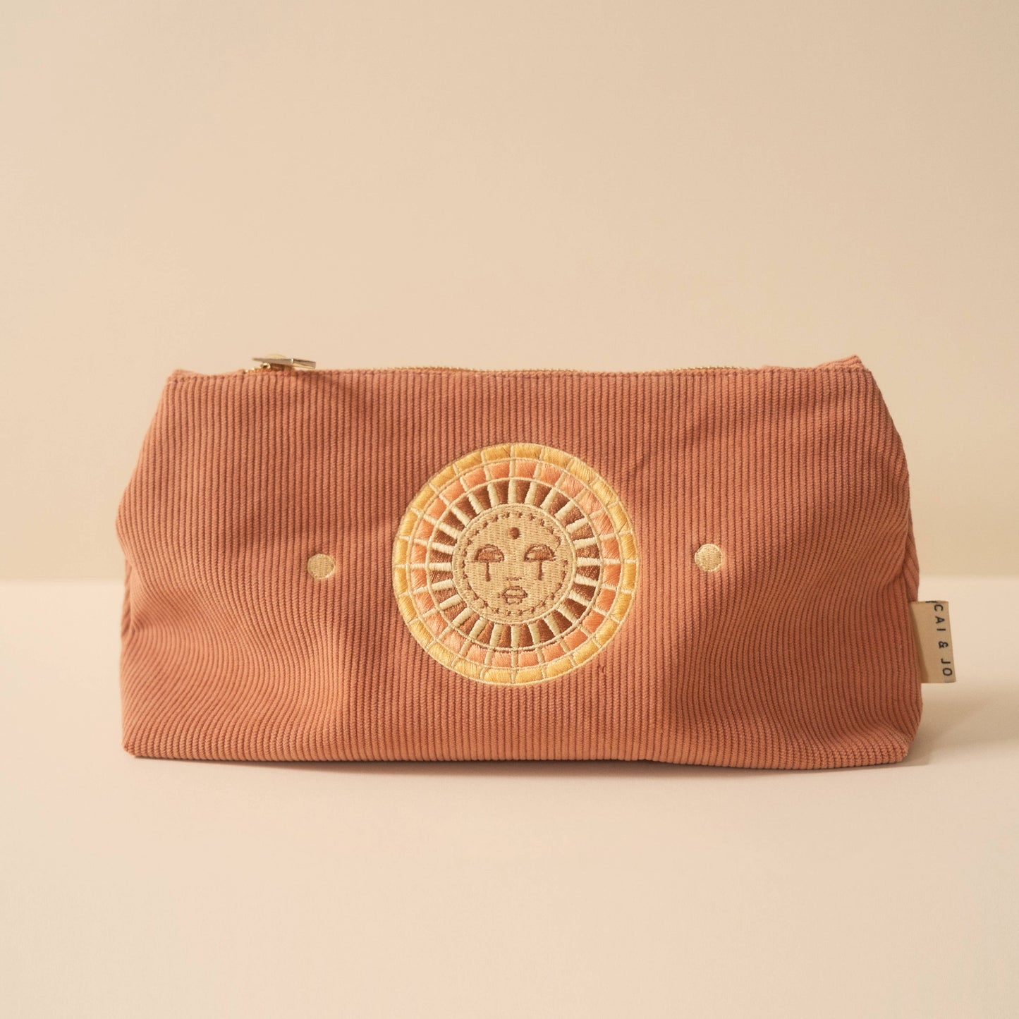 Brown corduroy pouch with a sun design on a beige background