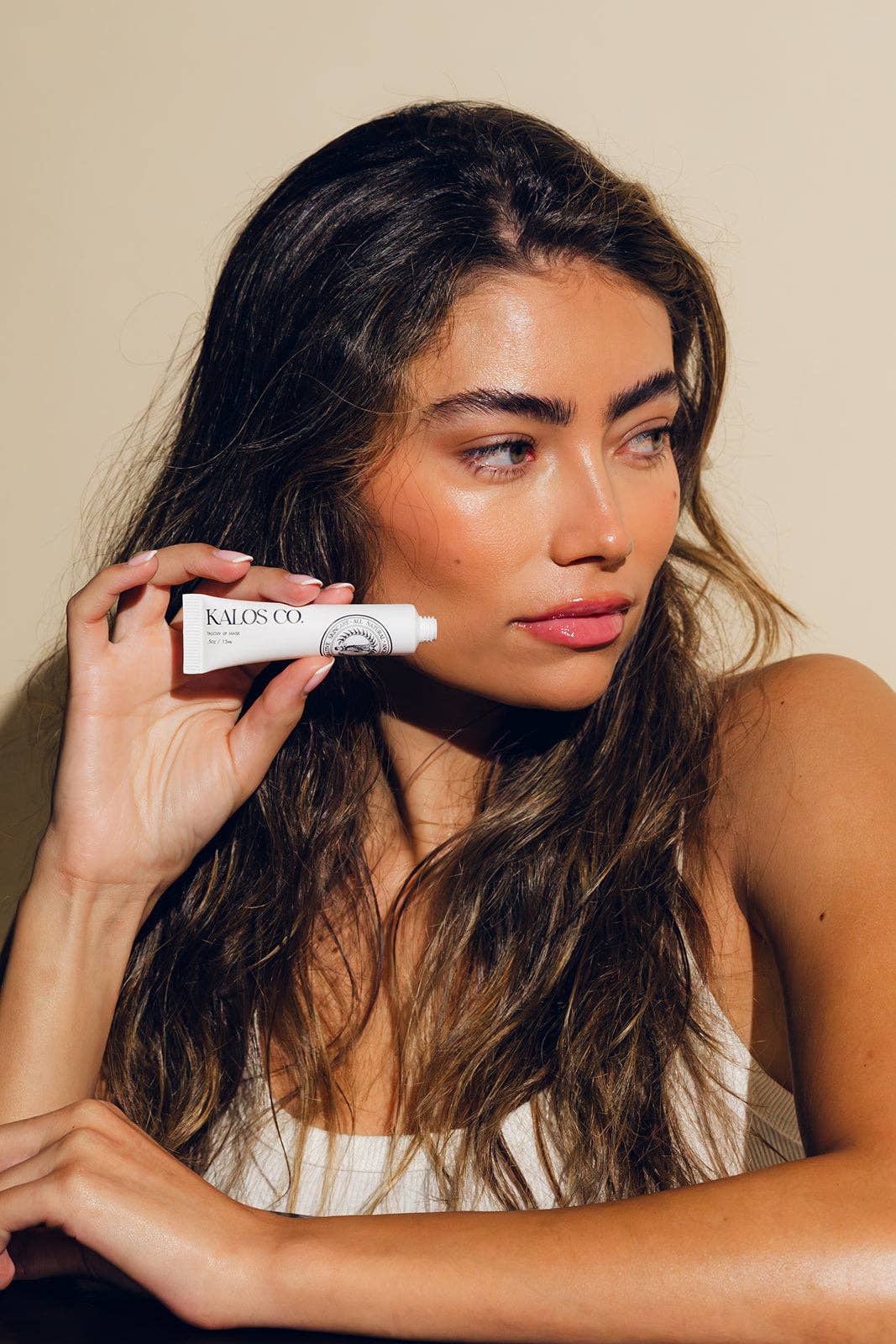 Woman holding a tube of Kiehl's lip balm against a neutral background