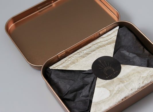 Open bronze-colored tin with marble-patterned interior and black label on a dark background