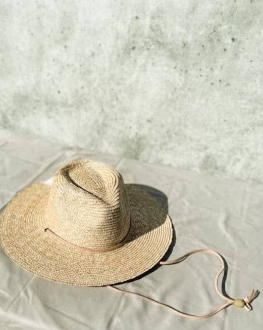 Beige straw hat with a wide brim on a light gray textured background