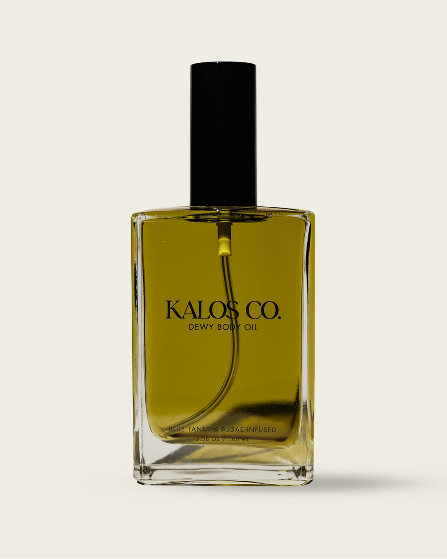 Glass bottle of Kalos Co. dewy body oil on a light gray background