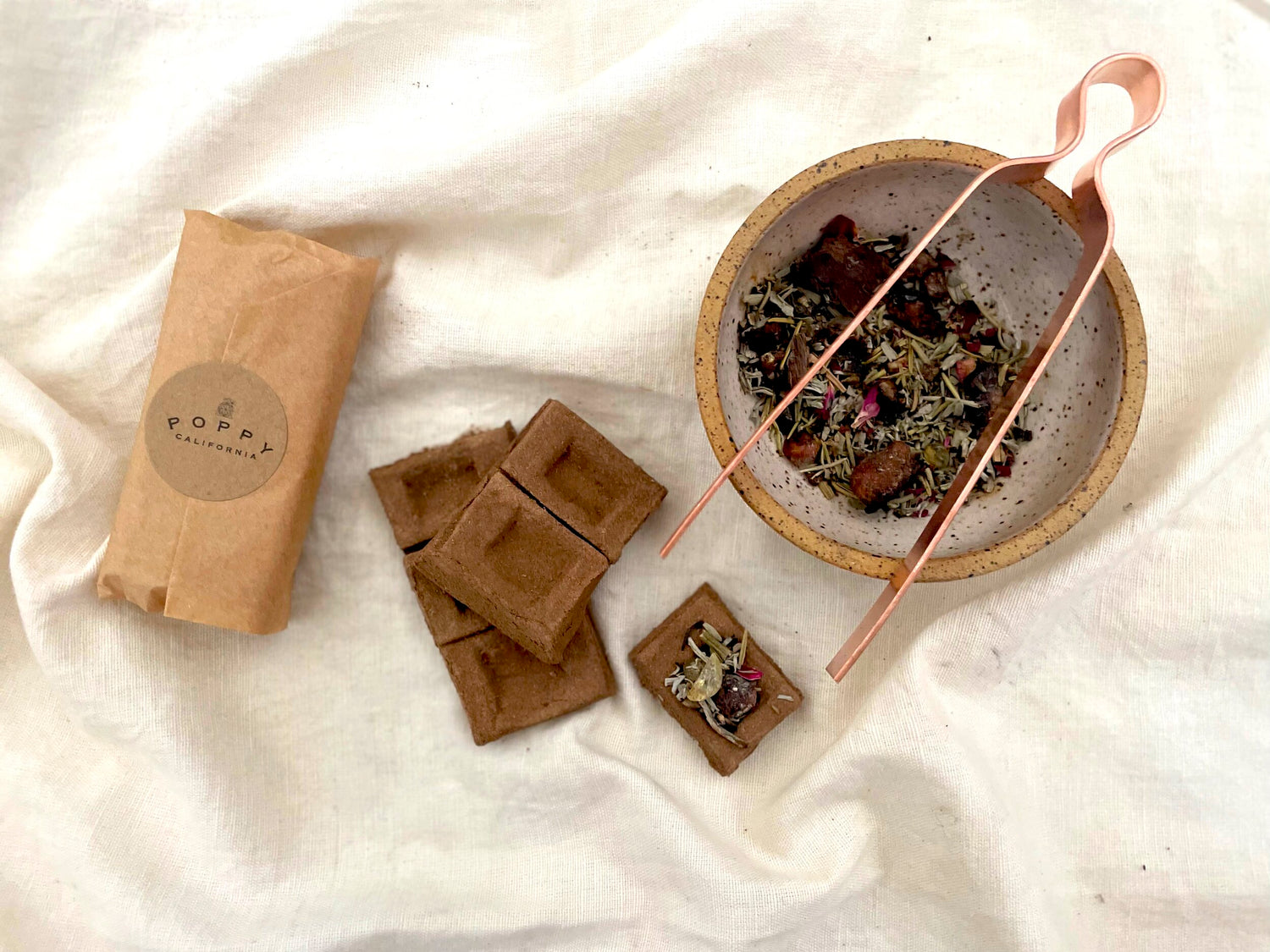 incense bowl filled with loose incense herbs on a cream cloth burning 