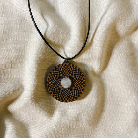 a wooden pendant with engraving of the inside of a sunflowers sacred geometry