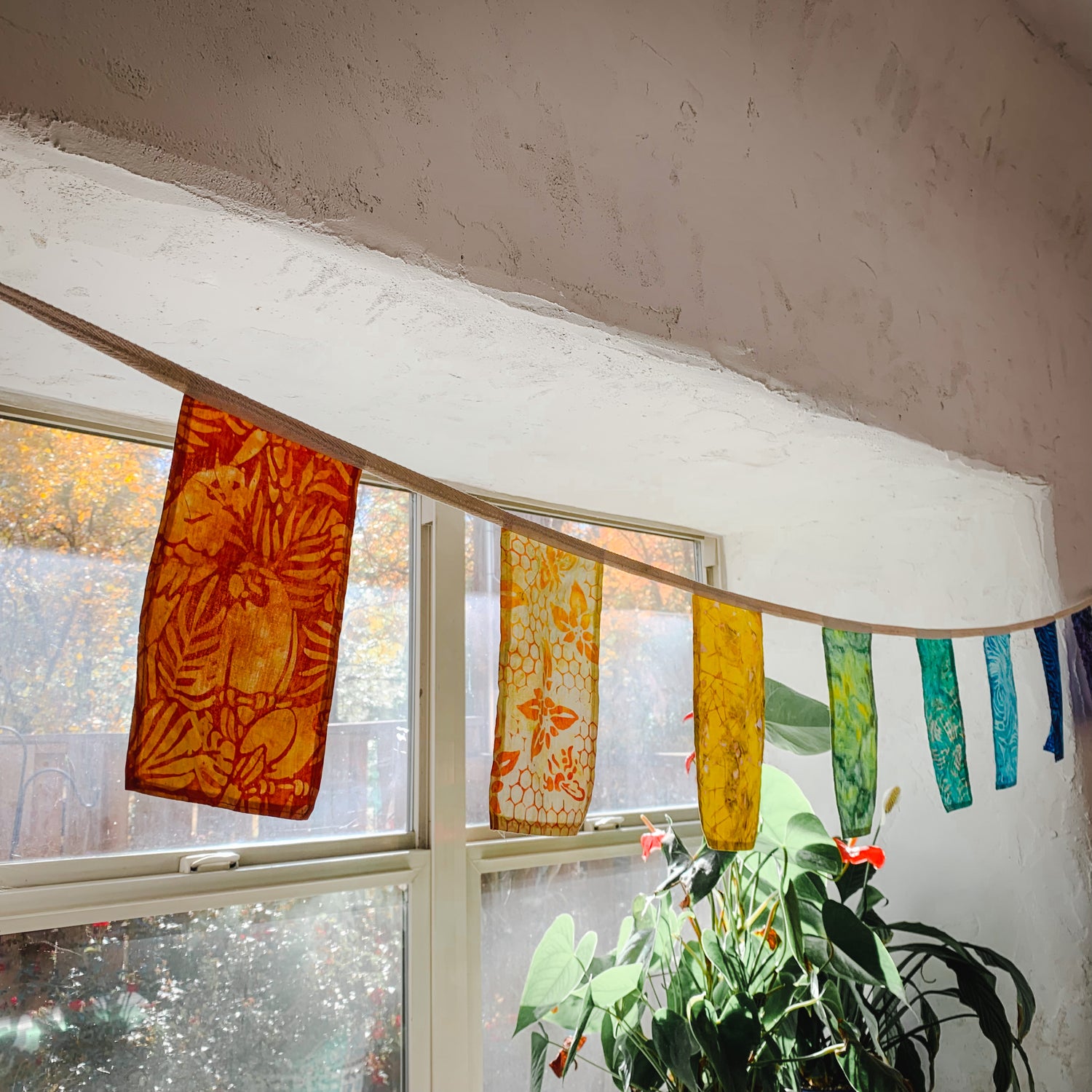 handmade rainbow bunting flags are draped across an old cabin window
